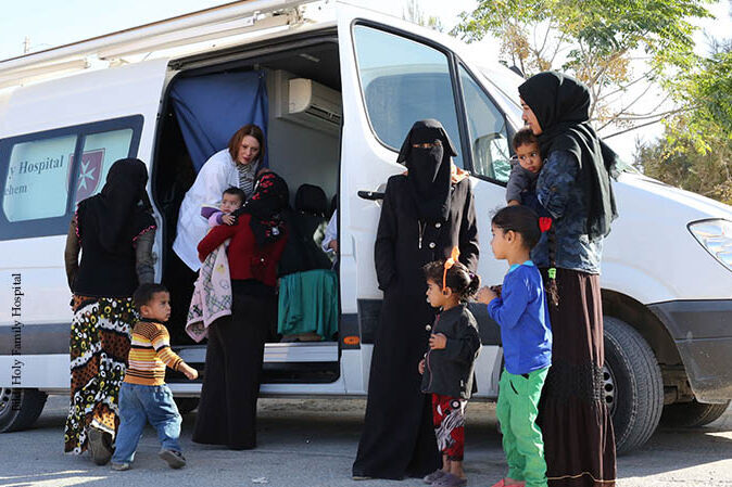 Verschleierte Frauen stehen mit ihren Kindern vor einem kleinen Bus